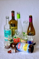 Das Bild zeigt mehrere Verpackungsglser und Flaschen in unterschiedlichen Farben, z. B. von Rapsl, Ahornsirup, Weinflaschen, Gemsekonserven und Medikamentenflschchen