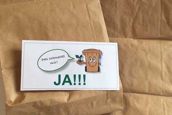 Erlaubte Papiertten fr die Biotonne mit einem Schild von BEN der Biotonne mit Sprechblase "Das schmeckt mir" sowie in groen grnen Buchstaben das Wort JA darunter. Bildrechte EBA