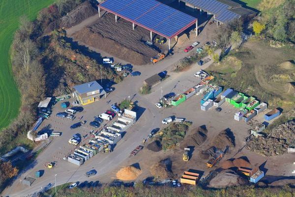 Luftbild der Grnkompostierungsanlage Kssaberg mit Recyclinghof von Erich Meyer. Vorne links  befindet der Recyclinghof mit den Boxen und den Altkleidercontainern. Dahinter ist das Betriebsgebude zu sehen. Im vorderen rechten Bereich befinden sich Hgel mit verschiedenen Materialien wie Erde, Sand, Holzschnitzel etc., die fr den Gartenbau bentigt werden. Im Hintergrund links ist der Abgabeort fr den Grnschnitt zu sehen, sowie Hallen mit dem zum Teil bereits aufbereiteten Kompost.