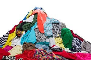 Das Bild zeigt verschiedene bunte Kleidungsstücke, die zu einem Berg aufgetürmt sind.