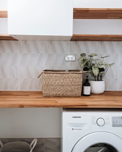 Auf dem Bild sind Holzregale mit einem Korb und einem Blumentopf zu sehen. Unter dem unteren Holzregal steht eine Waschmaschine und links daneben ein Wäschekorb. pexels-rachel-claire-4993073