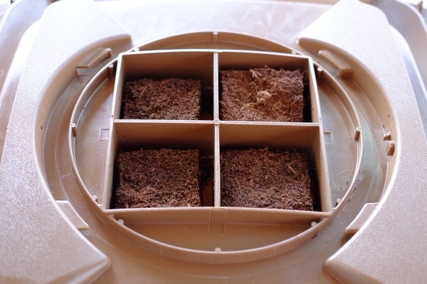 Das Bild zeigt den geöffneten, braunen Filterdeckel für eine Biotonne 60 oder 120 l mit quadratischen Presslingen aus Kokossubstrat darin. Das Bild zeigt den geöffneten, braunen Filterdeckel für eine Biotonne 60 oder 120 l mit quadratischen Presslingen aus Kokossubstrat darin.