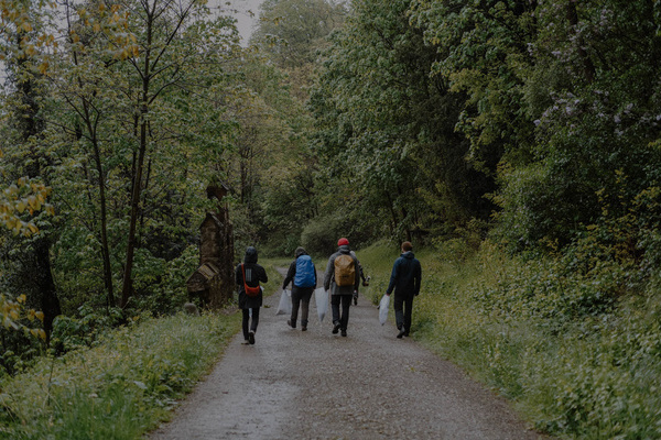 Das Bild zeigt einen Waldweg mit vier Personen darauf. Die Personen halten Mülltüten in der Hand, mit Abfall, der unterwegs gesammelt wurde. Copyright Patron e. V. Das Bild zeigt einen Waldweg mit vier Personen darauf. Die Personen halten Mülltüten in der Hand, mit Abfall, der unterwegs gesammelt wurde. Copyright Patron e. V.