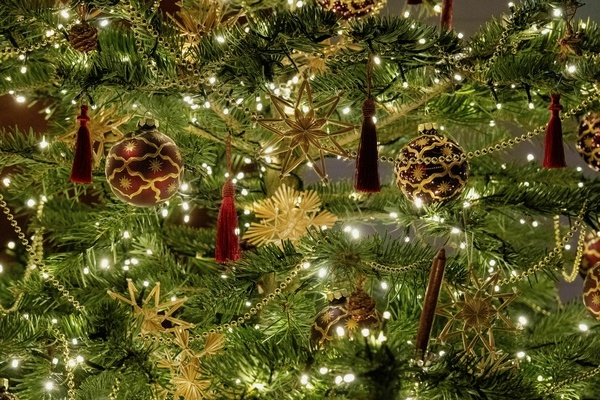 Das Bild zeigt Teile eines Weihnachtsbaums, geschm�ckt mit Strohsternen, rot/goldenen Kugeln, roten Troddeln und Kerzen sowie einer goldenen Kette, Pexels by David Ruh